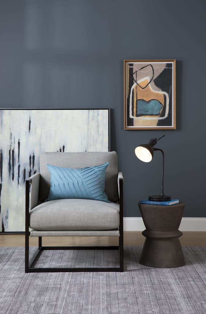 Two pieces of artwork behind chair in living room setting.