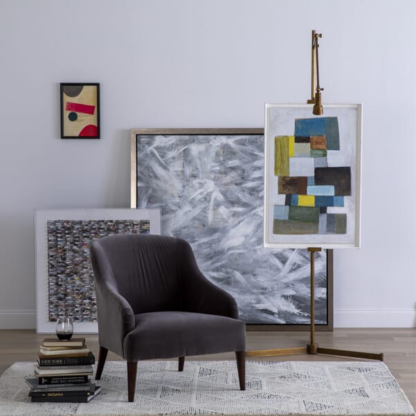framed artwork against a wall with a chair and a stack of books