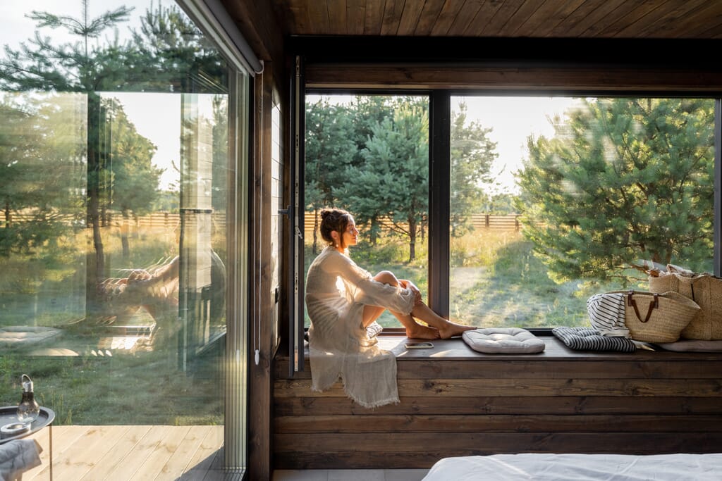 Woman sitting by window with eyes closed 