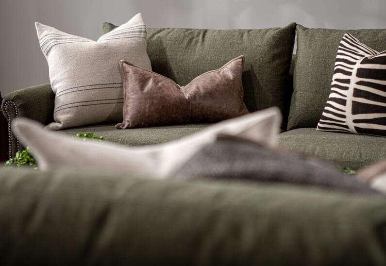 green couch that is decorated with different sizes and colors of pillows