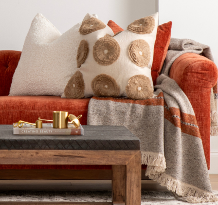 orange sofa with pillows and a throw