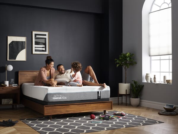 family on Tempur-Pedic mattress on wood bed frame in room shot
