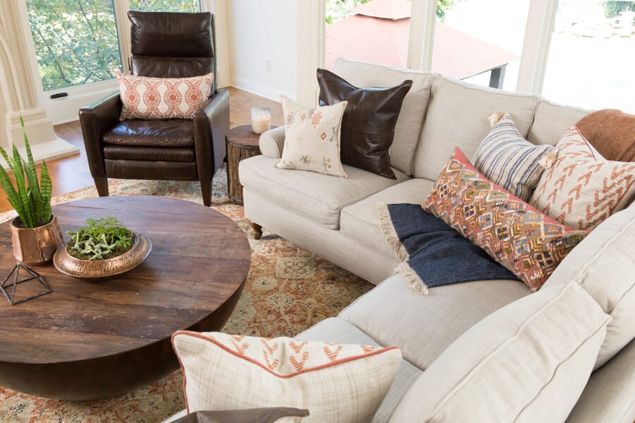 Birds eye view of neutral sectional with brown leather chair and wood coffee table in a living room setting.